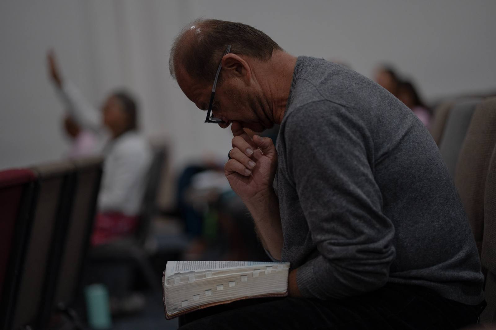 Un hermano ora con su Biblia abierta durante el servicio.