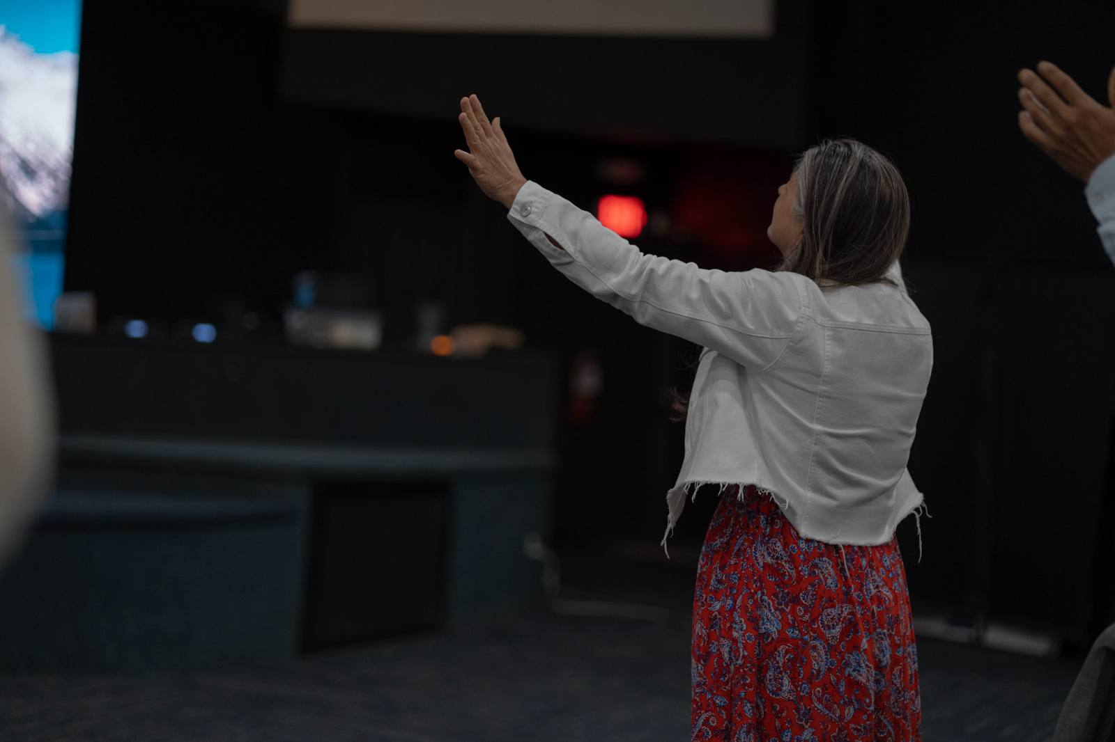 Una hermana adora de pie frente a la plataforma durante el servicio.